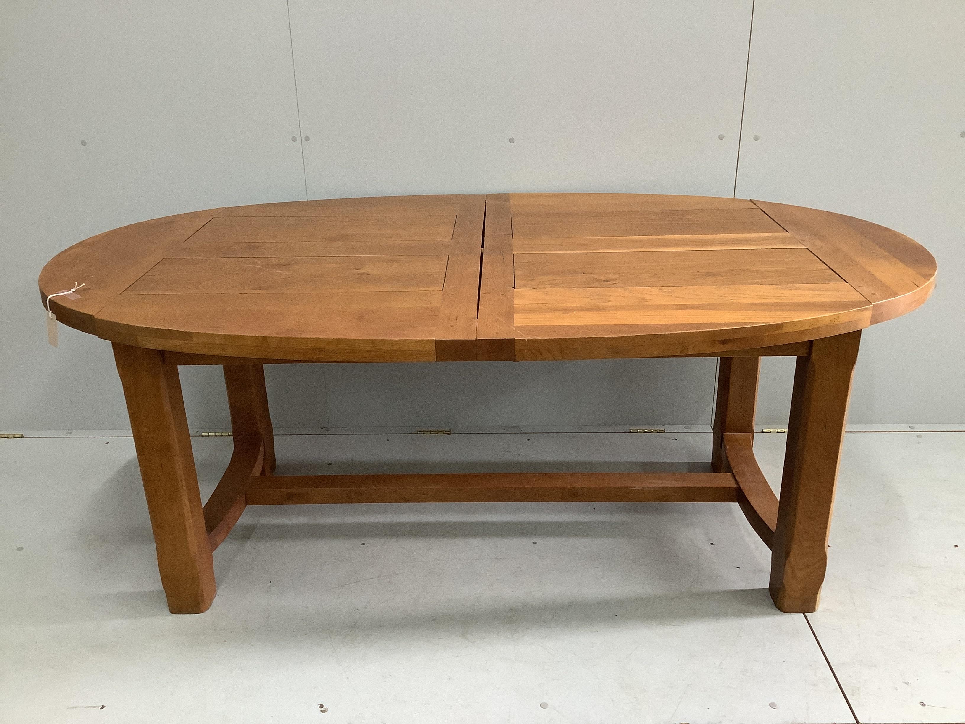 A contemporary oval oak extending dining table in the style of Pierre Chapo, 270cm extended, two spare leaves, depth 110cm, height 75cm